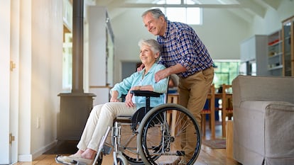 Una mujer sonriendo en su silla de ruedas mientras su marido la abraza