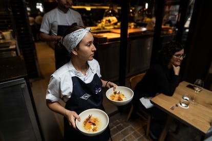 Una mesera lleva dos platillos a clientes del restaurante El Chato.