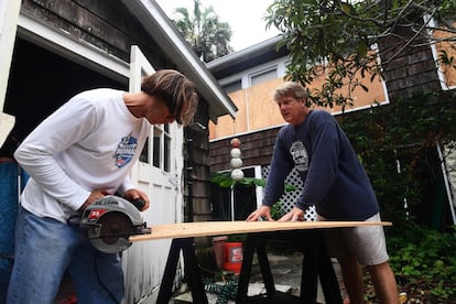 Dos personas protegen su casa con tablas de madera, en Atlantic Beach, Florida. 