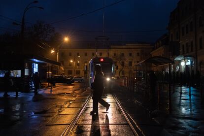 Una persona cruzaba una calle por la que circulaba un tranvía en el barrio de Podil, durante los apagones de energía en el centro de Kiev (Ucrania), el domingo.