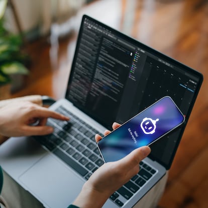 Asian woman using AI chatbot virtual assistance app on smartphone to assist her while working on laptop. Using AI technology while working at home. Online robot system. Concept of VR and AR technologies. People, AI, innovation and technology