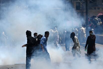 Pakistan Tehreek-e-Insaf party activists and supporters of former prime minister Imran stand amid teargas fired by police during a protest against the arrest of their leader, in Peshawar on May 10, 2023.