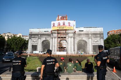 Agentes de la Policía Nacional junto a la lona colgada por Greenpeace en la Puerta de Alcalá de Madrid, este martes. 