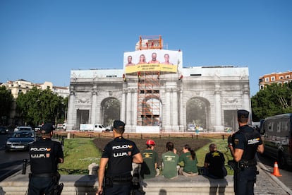Agentes de la Policía Nacional junto a la lona colgada por Greenpeace en la Puerta de Alcalá de Madrid, este martes.
