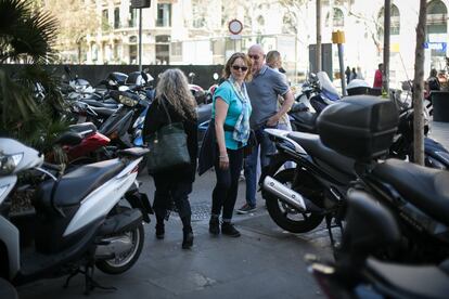 Vianants intenten passar entre les motos aparcades a la vorera.