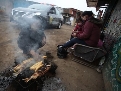 Una mujer asa unos pescados en el asentamiento de Cantagallo, en Lima, el pasado 23 de junio.