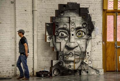 Un hombre pasa por delante de un grafiti del artista JR, expuesto en el centro cultural La Condition Publique, in Roubaix (Francia). La Condition Publique presenta una exposición dedicada al arte urbano.