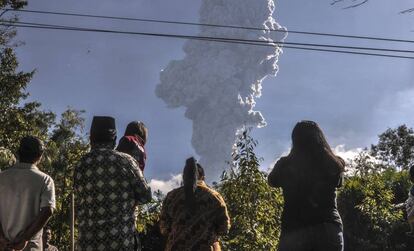 Varias personas observan la erupción del volcán Merapi, en Indonesia.