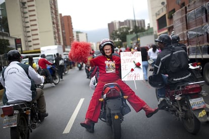 Una partidaria del presidente de Venezuela Hugo Chávez, Marlene Vanegas, de 72 años, conocida como "Little Red Riding Hood", en la parte trasera de una motocicleta con un cartel casero que dice en español: "El amor se paga con amor ", durante un acto con motivo del Día Internacional de la Mujer en Caracas, Venezuela.