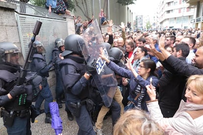 Votantes de un colegio electoral de Girona forcejean con agentes antidisturbios de la Policía Nacional que acudieron a clausurar el centro e incautarse de las urnas.