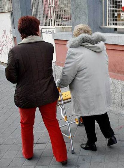 Una anciana va a votar junto a una voluntaria del PP.