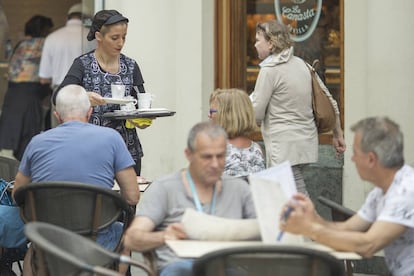 Una camarera sirve una mesa en una cafetería cétrica de Sevilla