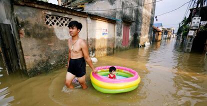 Un hombre traslada a su hija en una piscina hinchable por una calle inundada de Hanoi, Vietnam, tras una tormenta tropical.