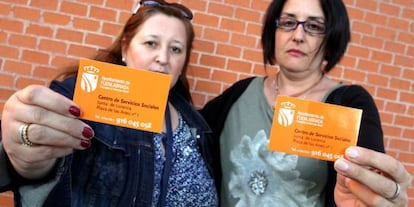 Two residents of Fuenlabrada hold up the social services card that is offered to undocumented migrants in their city.