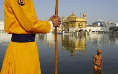 Un peregrino se baña en el estaque que rodea el templo dorado de Amritsar, santuario sagrado para los sijs.