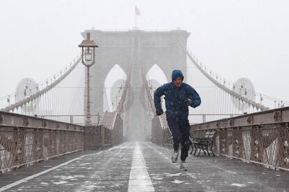 Um homem corre pela ponte de Brooklyn em Nova York nesta quinta-feira. Toda a Costa Leste dos Estados Unidos se prepara para uma tempestade de inverno que poderia alcançar proporções históricas. O Estado de Nova York declarou estado de emergência na zona sul de seu território ante a chegada do poderoso fenômeno meteorológico. A partir desta quinta-feira até o fim da semana, o temporal subirá pelo noroeste, e se prevê que uma abrupta queda da pressão atmosférica a transforme numa “bomba ciclônica” – ou ciclogênese explosiva – que soma ao frio fortes rajadas de vento, desencadeando perigosas tempestades de neve.