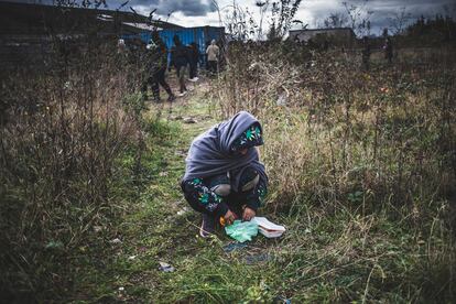 Un inmigrante afgano come junto a la cola de gente que recibe comida de las asociaciones de ayuda a los inmigrantes de Calais
