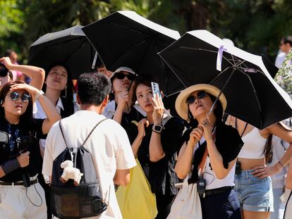 Un grupo de turistas asiáticas se protegen del sol, el pasado agosto en Barcelona.