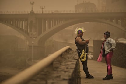 Dos personas disfrazadas charlan bajo la calima en Santa Cruz de Tenerife. El Sábado de Carnaval ha sido suspendido debido a la nube de polvo procedente del Sahara.