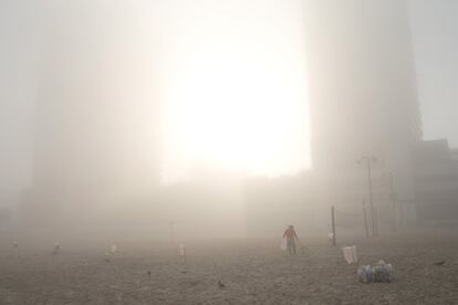 Un trabajador limpia la playa de Tel Aviv (Israel) bajo una densa niebla.