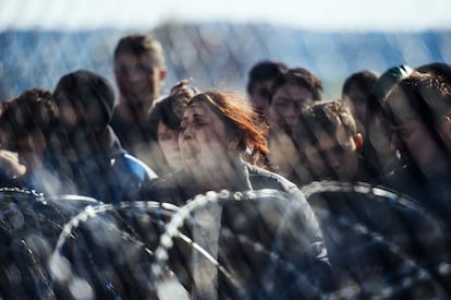 Una dona protesta amb altres migrants darrere d'una tanca a la frontera entre Grècia i Macedònia, prop de Gevgelija (Macedònia), el 2 de març del 2016.