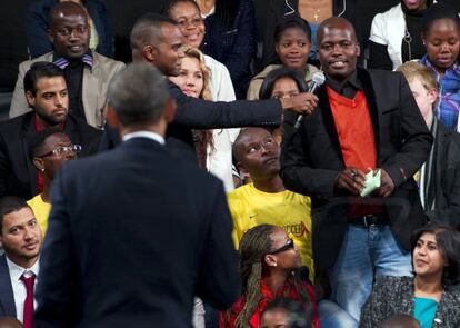 Obama (de espaldas) escucha a un joven en la Universidad de Soweto.