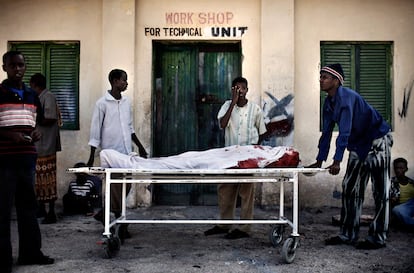 Un grupo de hombres espera a un vehculo para llevar a casa y enterrar a un a un pariente muerto durante un enterramiento en Mogadiscio.