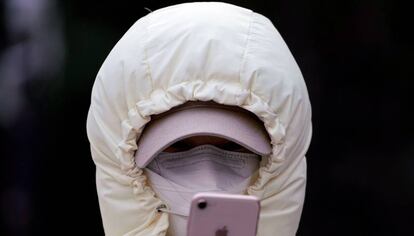 Una mujer con una máscara revisa su teléfono móvil en Shanghai, China.
