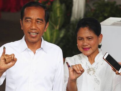 El presidente indonesio, Joko Widodo, junto a la primera dama, Iriana Joko Widodo muestran sus dedos después de haber depositado su voto este miércoles en Jakarta.