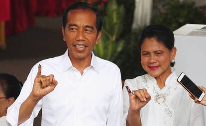 El presidente indonesio, Joko Widodo, junto a la primera dama, Iriana Joko Widodo muestran sus dedos después de haber depositado su voto este miércoles en Jakarta.