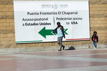 Una mujer haitiana y su hijo pasan frente el puesto fronterizo de El Chaporral, en Tijuana para cruzar a los EEUU.