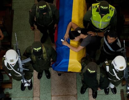 A woman cries over the coffin of one of six police killed during a FARC attack.