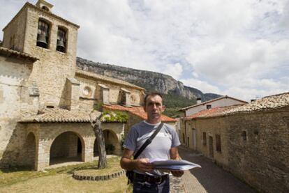 El exalcalde de Ziritza (Navarra) muestra la documentación sobre los edificios de su pueblo, con la iglesia a su espalda.