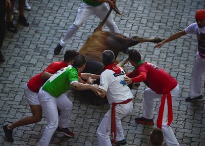 Uno de los toros cae al suelo durante el quinto encierro en Pamplona.  