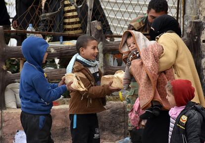 Dos niños ofrecen comida a una mujer que huye de la parte oriental de Alepo.