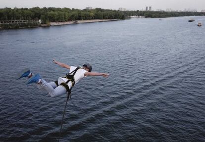 Un hombre salta al río Dnipro con una cuerda desde un puente en Kiev (Ucrania).