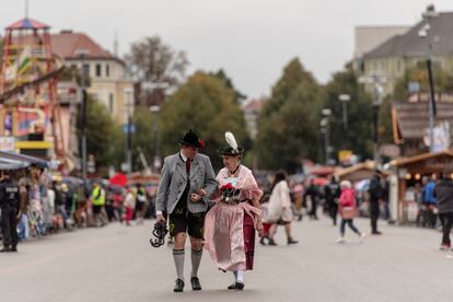 Dos personas con traje tradicional bávaro pasean por la edición de 2022 del Oktoberfest, en Múnich. 