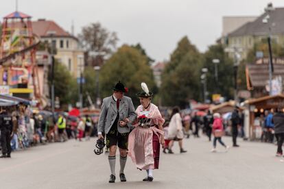 Dos personas con traje tradicional bávaro pasean por la edición de 2022 del Oktoberfest, en Múnich.