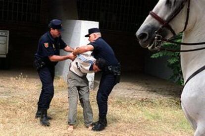 Dos agentes detienen a un inmigrante en el campus de la Universidad Pablo de Olavide.