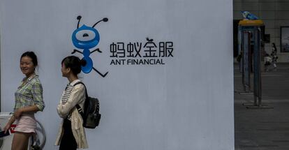 Dos jóvenes pasan junto al logo de Ant Financial, del grupo Alibaba.