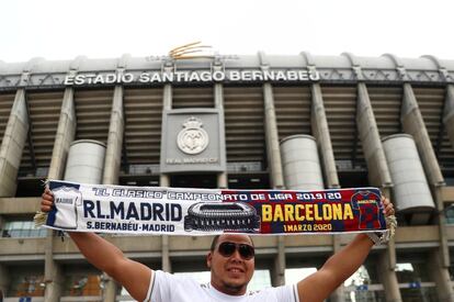 Un aficionado posa frente al estadio con una bufanda conmemorativa del encuentro entre el Real Madrid y el Barça.