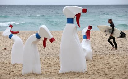 Un surfista pasa junto a una instalación 'Las botellas'en la costa en Sydney.