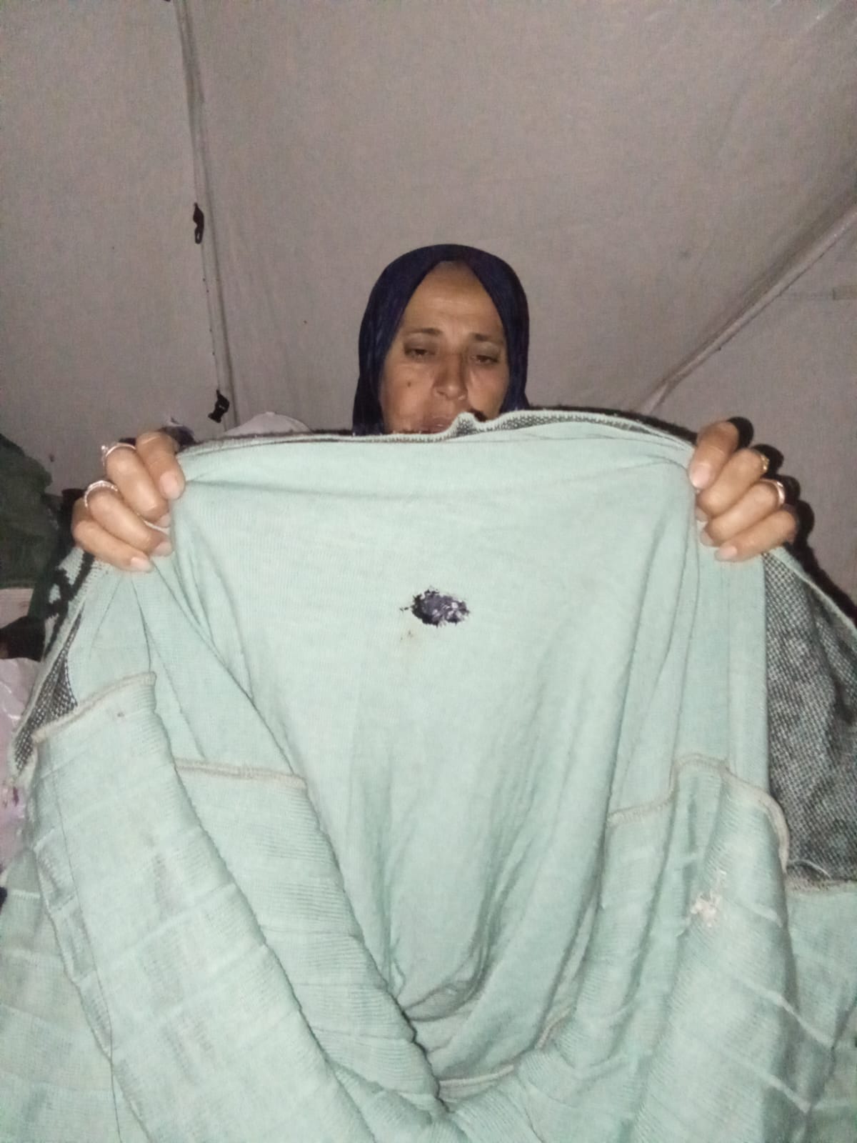 Um Raef Abu Salma, la madre de Amani, de 53 años, muestra los agujeros que dejaron los roedores en una de las prendas del ajuar de su hija.