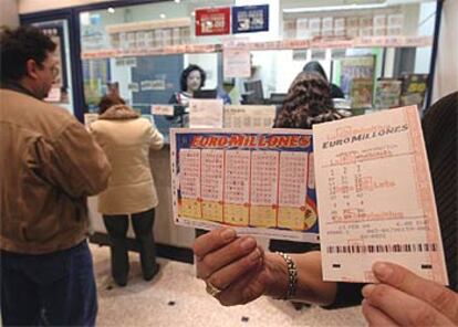 Un apostante muestra los boletos del nuevo Euromillones en una administración de lotería.