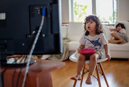 Una niña mira anuncios de comida en la televisión. 