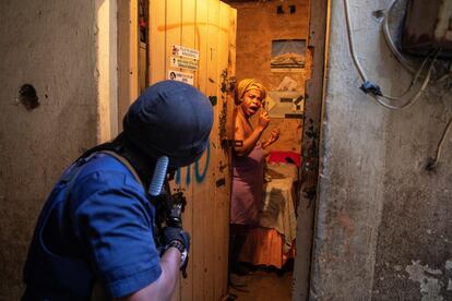 Una mujer reacciona después de que un policía irrumpiera en su habitación durante una redada policial en un edificio de viviendas secuestrado por las mafias inmobiliarias, en el centro de Johannesburgo, (Sudáfrica).