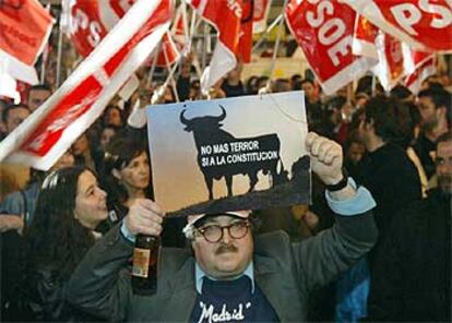 Un hombre, botella en mano, sostiene un cartel con el popular toro de una marca comercial con un mensaje político: "No más terror, sí a la constitución".
