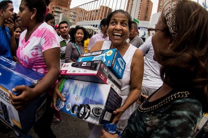 Decenas de personas sacan electrodom&eacute;sticos de una tienda.