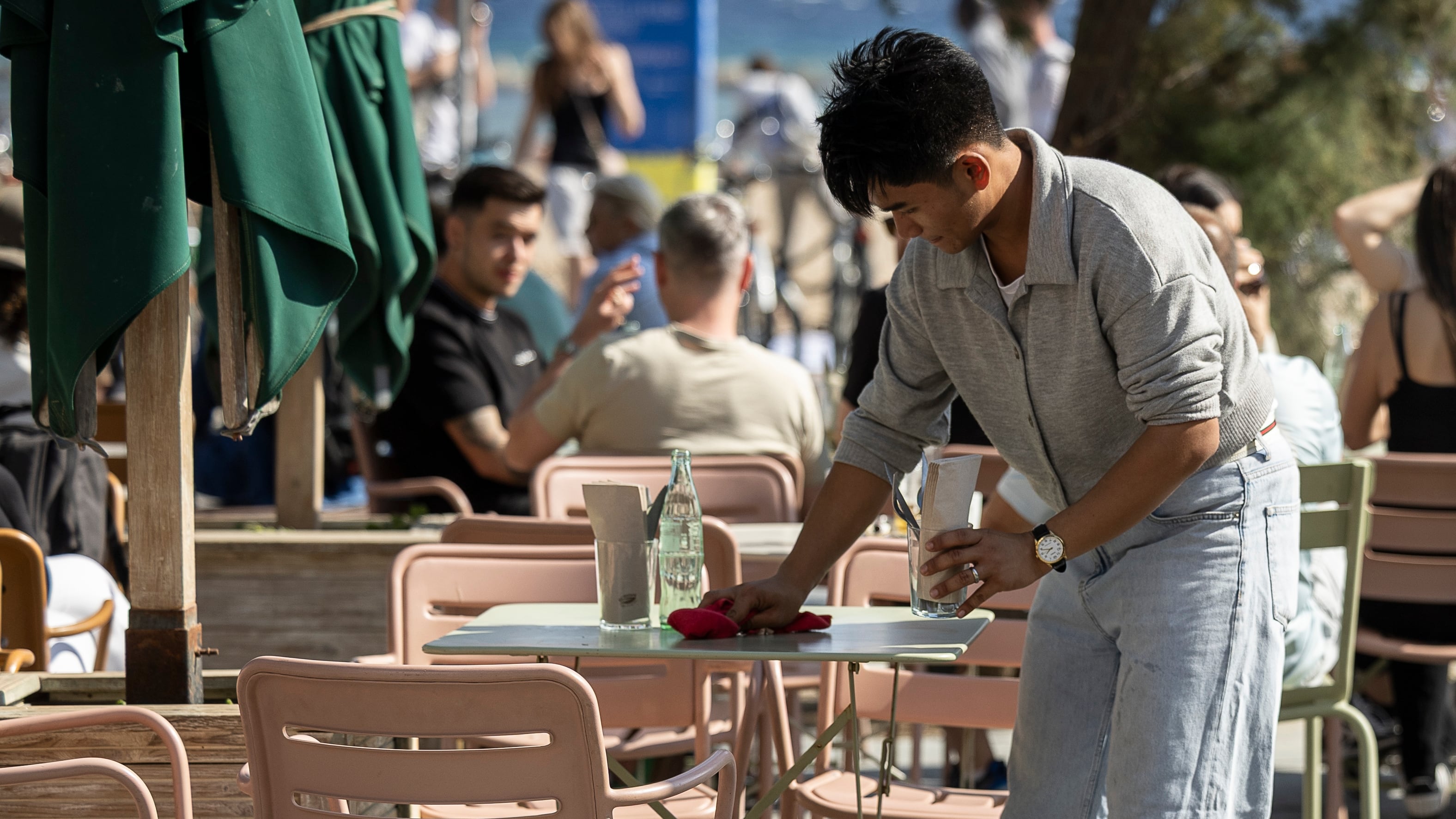 A waiter cleans a table on the terrace of a restaurant on the Barceloneta promenade. 

