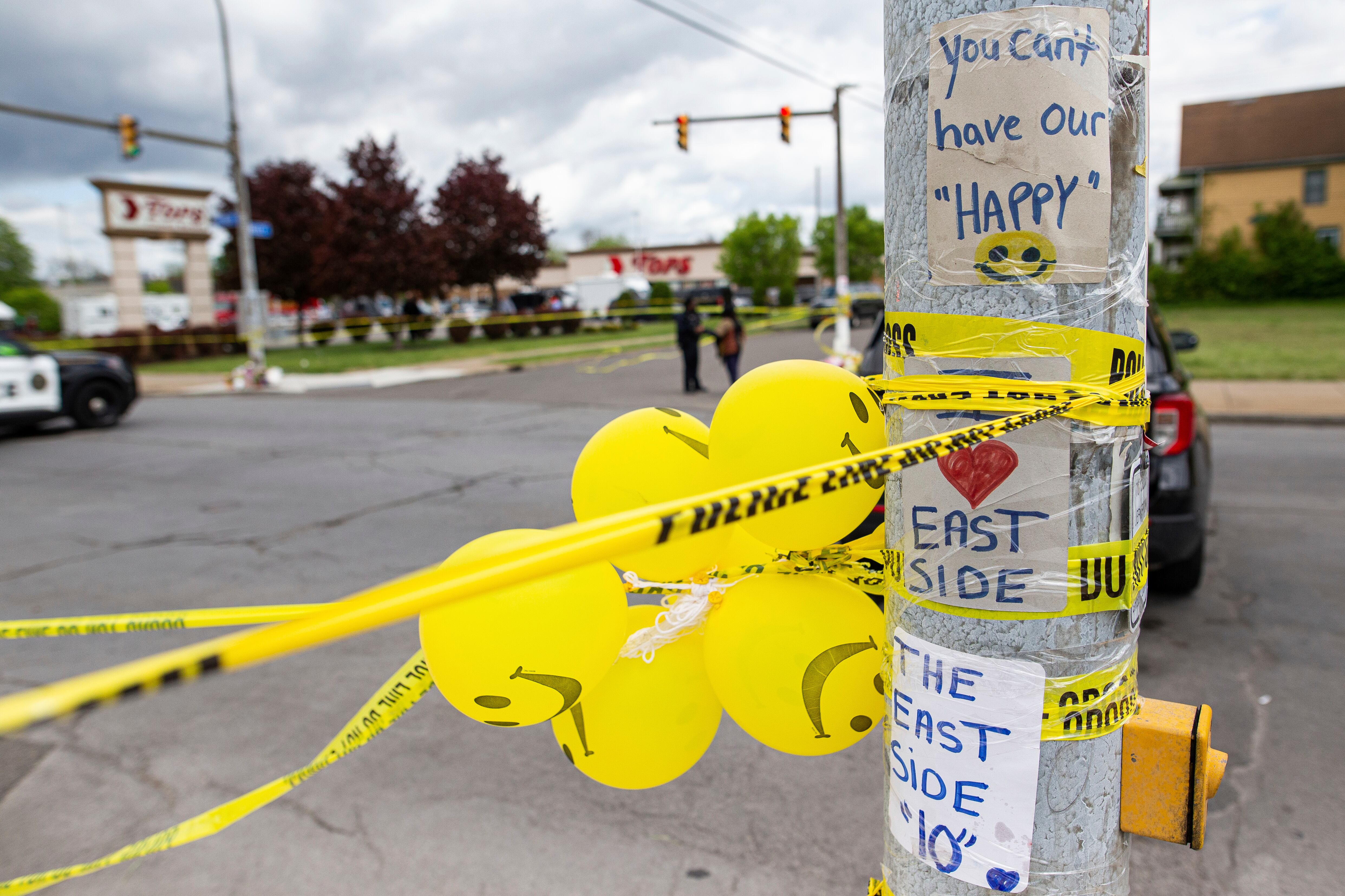 Letreros, globos y cinta policial se envuelven alrededor de un poste frente a Tops Friendly Market, el 17 de mayo de 2022, en Búfalo, Nueva York.